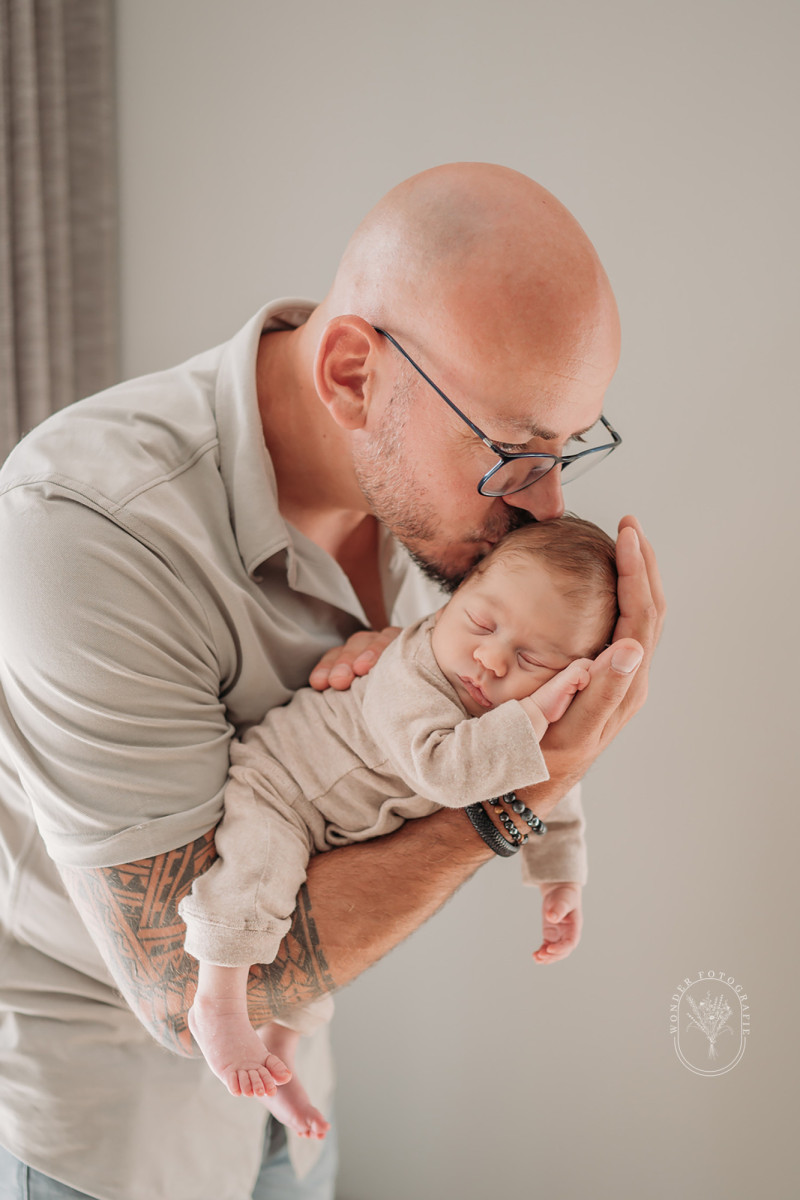 Vader houdt zijn pasgeboren baby vast tijdens een newborn fotoshoot aan huis