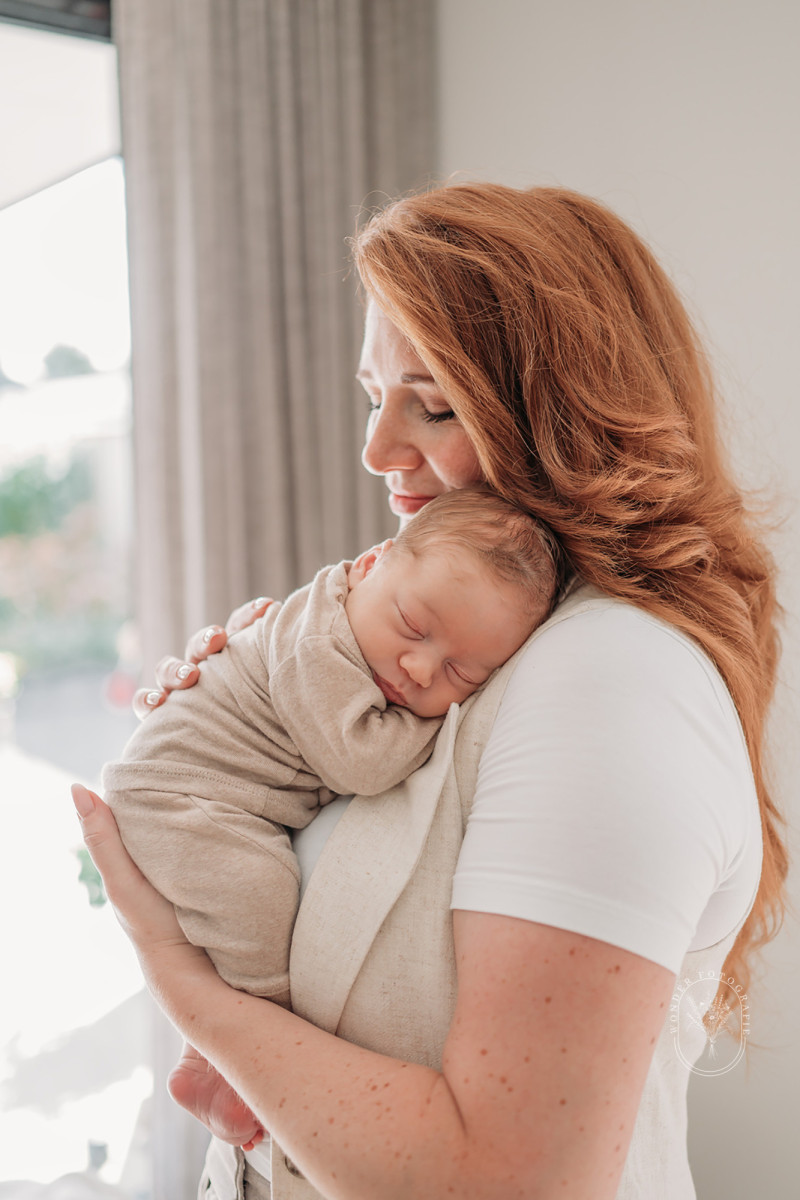 Moeder houdt haar pasgeboren baby vast tijdens een lifestyle newborn fotoshoot