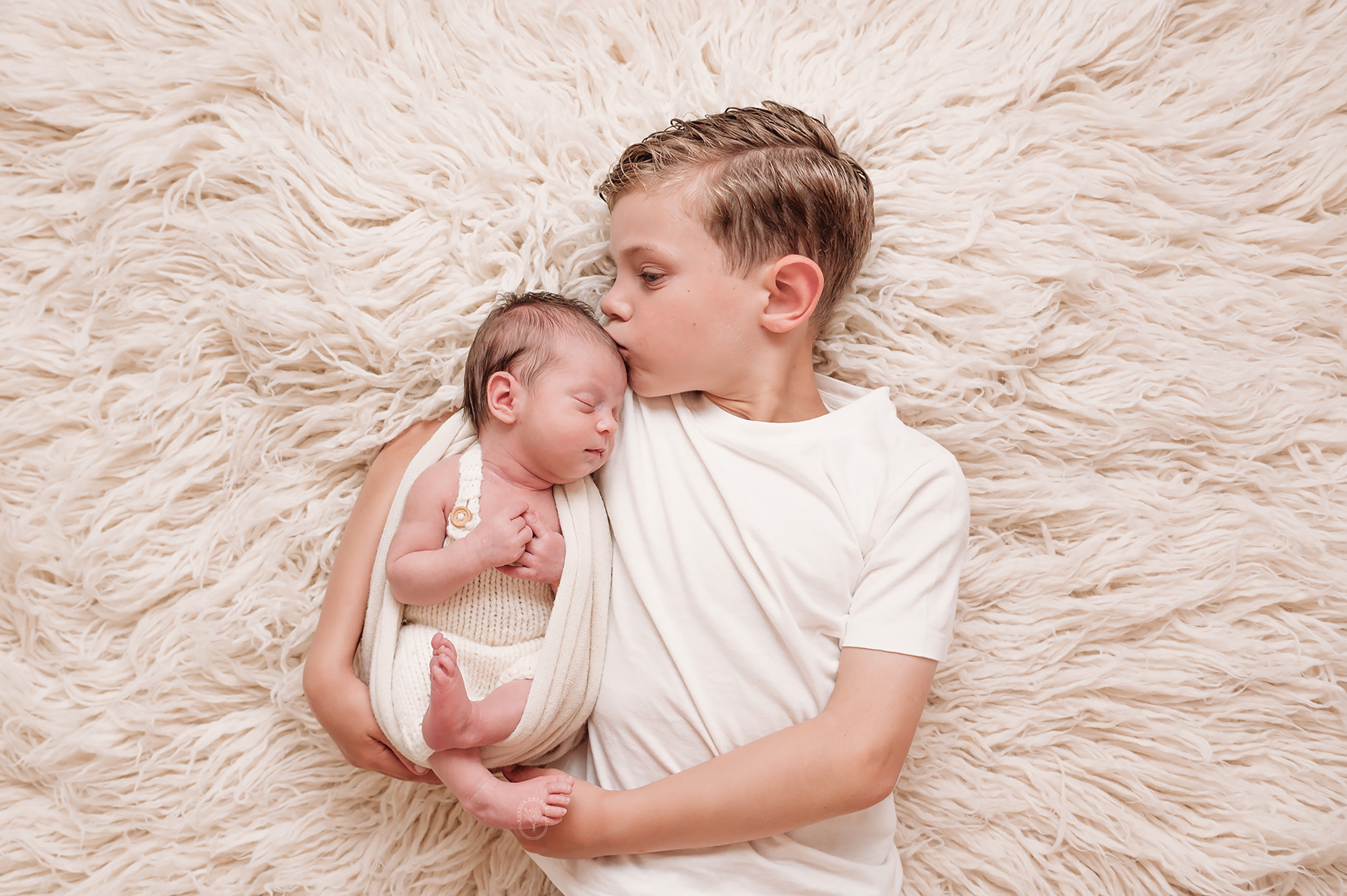 Trotse grote broer met pasgeboren baby tijdens newborn fotoshoot